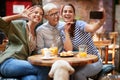 A group of female friends of different generations taking a selfie while they have a drink in the bar together after long time.