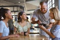 Group Of Female Friends Meeting Up In Restaurant Or Coffee Shop Being Served By Waiter Royalty Free Stock Photo