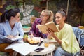 A group of female students doing university tasks while sitting and have a drink in a bar. Leisure, bar, outdoor, friendship