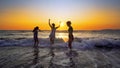 female teens having fun jumping and splashing down the beach at sunset