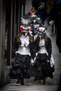 A group of females in medieval dresses and carnival masks walk at the street in Venice, Italy