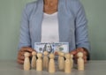 Group of figurines of people and businesswoman boss holding 100 dollars