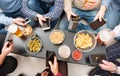 Group of firends looking the smartphone and taking an aperitif with beer and snack at home