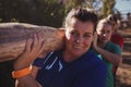 Group of fit women carrying a heavy wooden log during obstacle course training Royalty Free Stock Photo