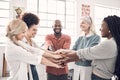 Group of five cheerful diverse businesspeople piling their hands together in an office at work. Happy business Royalty Free Stock Photo