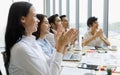 Group of five diversity businessmen, two men and three women sitting at meeting desk and clap their hands for the speaker