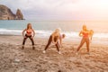 A group of five female friends are doing exercises on the beach. Beach holiday concept, healthy lifestyle Royalty Free Stock Photo