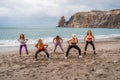 A group of five female friends are doing exercises on the beach. Beach holiday concept, healthy lifestyle Royalty Free Stock Photo