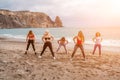 A group of five female friends are doing exercises on the beach. Royalty Free Stock Photo