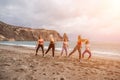 A group of five female friends are doing exercises on the beach. Royalty Free Stock Photo