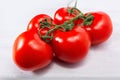 Group of five fresh, ripe red tomatoes, still connected through the green stem Royalty Free Stock Photo