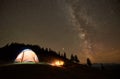 Friends resting beside camp, campfire under night starry sky Royalty Free Stock Photo