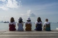 Five happy girls sit on wooden pier looking to the sea on the vacations concept Royalty Free Stock Photo