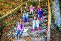 Group of five little girls sitting on the stone staps and playing with puppies in the forest