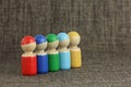 Group of five multicolored wooden toy people are lined up in a diagonal, cloth or fabric background with copy space