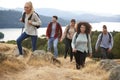 A group of five young adult friends smiling while hiking to a mountain summit