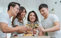 Group four Asian cheerful casual smiley friends making toast or cheers clinking wine glasses together while having party with fun