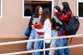 Group of four college student girls walking and talking together with intimate in front of school building. Learning and Royalty Free Stock Photo