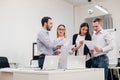 Group of four diverse men and women in casual clothing talking in office Royalty Free Stock Photo