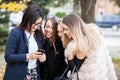 Group of four girl friends looking at phone on the selfie they w