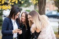 Group of four girl friends looking at phone on the selfie they w