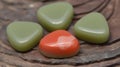 a group of four heart shaped rocks sitting on top of a wooden table next to a red and green heart shaped rock on top of a piece