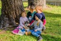 Group of four kids playing with husky puppy in the park