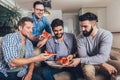 Four male friends drinking beer and eating pizza at home Royalty Free Stock Photo