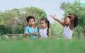 Group of four mixed race African and caucasian little cute kids sitting, playing in outdoor green park for picnic, eating fruit,