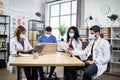 Four multiracial doctors examining medical record of patient, working in modern office