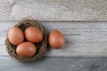 Group four natural chicken eggs from farm products in bird nest on vintage wooden background. Advertising image Easter or food