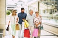 Group of four people with adults and seniors buying and doinng shopping in the mall together looking stores and carriyng gifts or Royalty Free Stock Photo