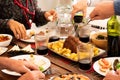 Group of four people eating and drinking together at home - celerbating something with chicken and wine - hands taking food from