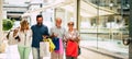 Group of four people going shopping together holding shopping bags with presents or gifts for christmas - buying clothes and more Royalty Free Stock Photo