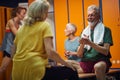 Group of four people in gym locker room, senior man and woman having a joyful conversation sitting facing each other