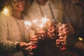 Group of four people having fun and enjoying holding glasses of champagne and sparklers celebrating the happy new year together Royalty Free Stock Photo