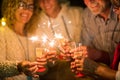 Group of four people having fun and enjoying holding glasses of champagne and sparklers celebrating the happy new year together Royalty Free Stock Photo