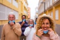 Group of four people respecting the social distance outdoors taking off their medical and surgical mask after covid 19 annd