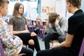 Four teenagers sitting together in a circle during psychotherapy session at school