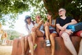 Group of four tourists sitting under tree near temple in thailand