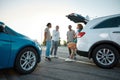 A group of four young casually dressed people speaking to each other smiling and standing together outside on a parking Royalty Free Stock Photo