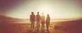 Group of four young people standing close to the beach in the bright sunshine. Vacation time, traveling and having fun together