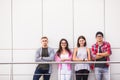 Group of four young smiling people wearing stylish casual clothing looking at camera standing in light office or university. Royalty Free Stock Photo