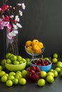 A group fresh fruits of spring,apricot,cherry,plum and strawberries in the bowls at the black background Royalty Free Stock Photo