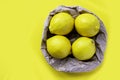 Group of fresh lemon in recycling paper bag. Eco packing concept. Four ripe lemon on yellow background. Royalty Free Stock Photo