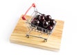 Group of fresh red cherries in a small shopping cart on a wooden board Royalty Free Stock Photo