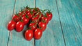 Group of fresh red tomatoes with green stem vines, on wooden boards painted blue, space for text right side Royalty Free Stock Photo