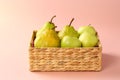 Group of fresh, ripe and juicy apples and pears in a water hyacinth basket against pink background