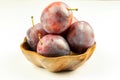 Group of fresh ripe big plums in natural wooden bowl on the white background Royalty Free Stock Photo