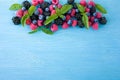 Group of fresh summer berries with basil`s on a blue background. Ripe blueberries, raspberries and blackberries. Royalty Free Stock Photo